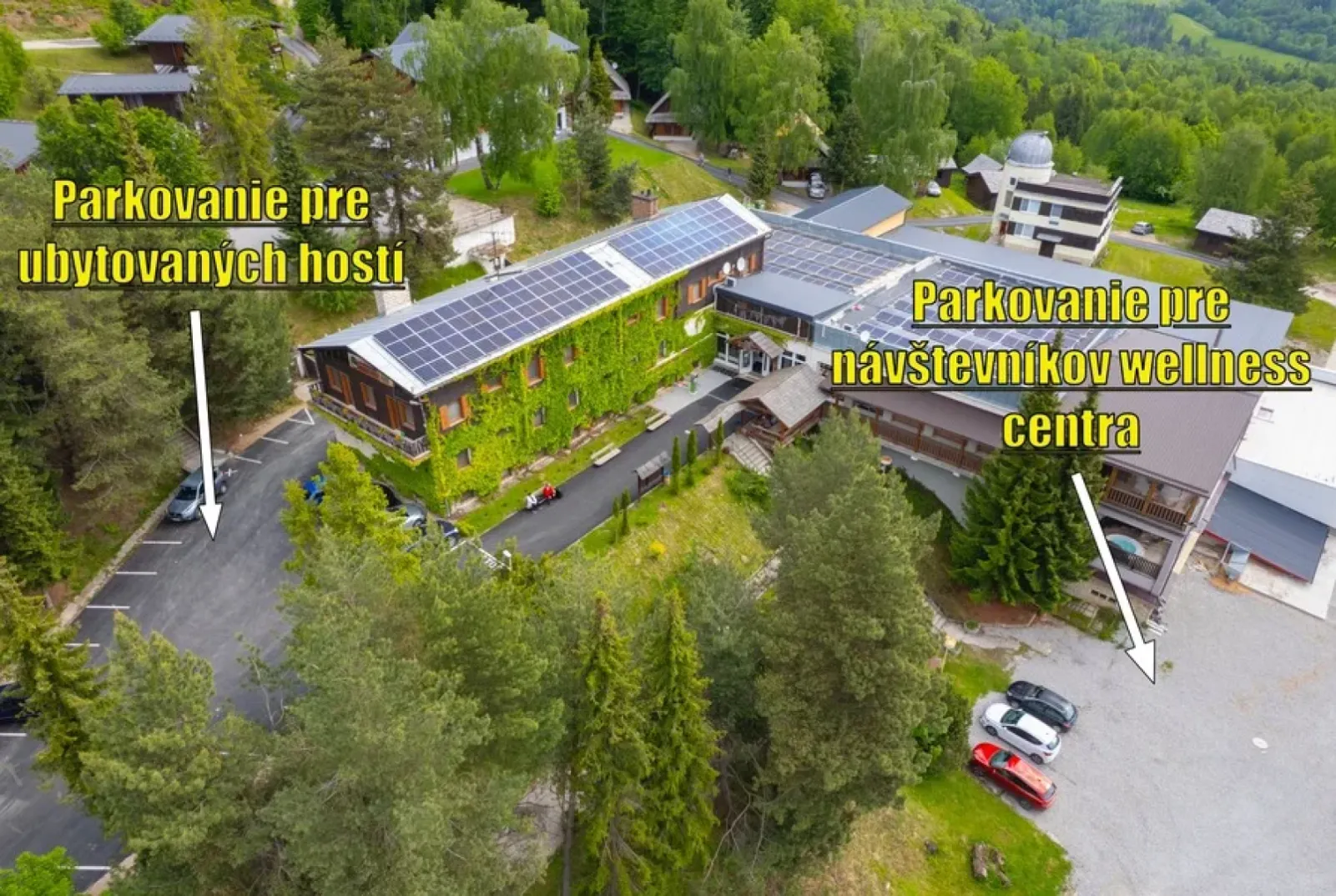 An aerial view of the Predná Hora resort, with the car park and cars between the buildings and the forest