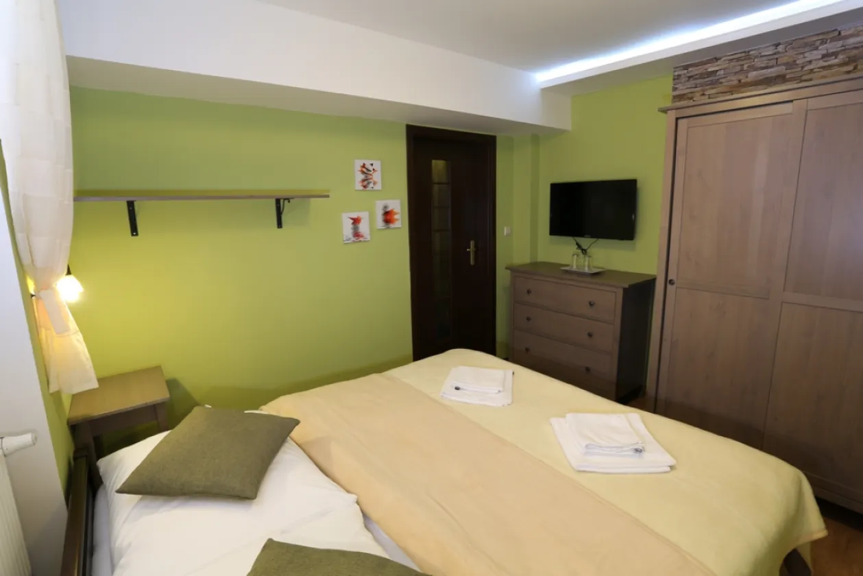 A room in the guest house with wood panelling and a large photograph of Muránska planina above the bed