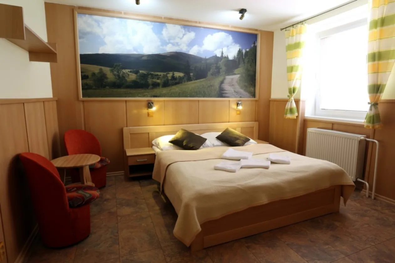A double room with an extra bed, a television and a coffee table