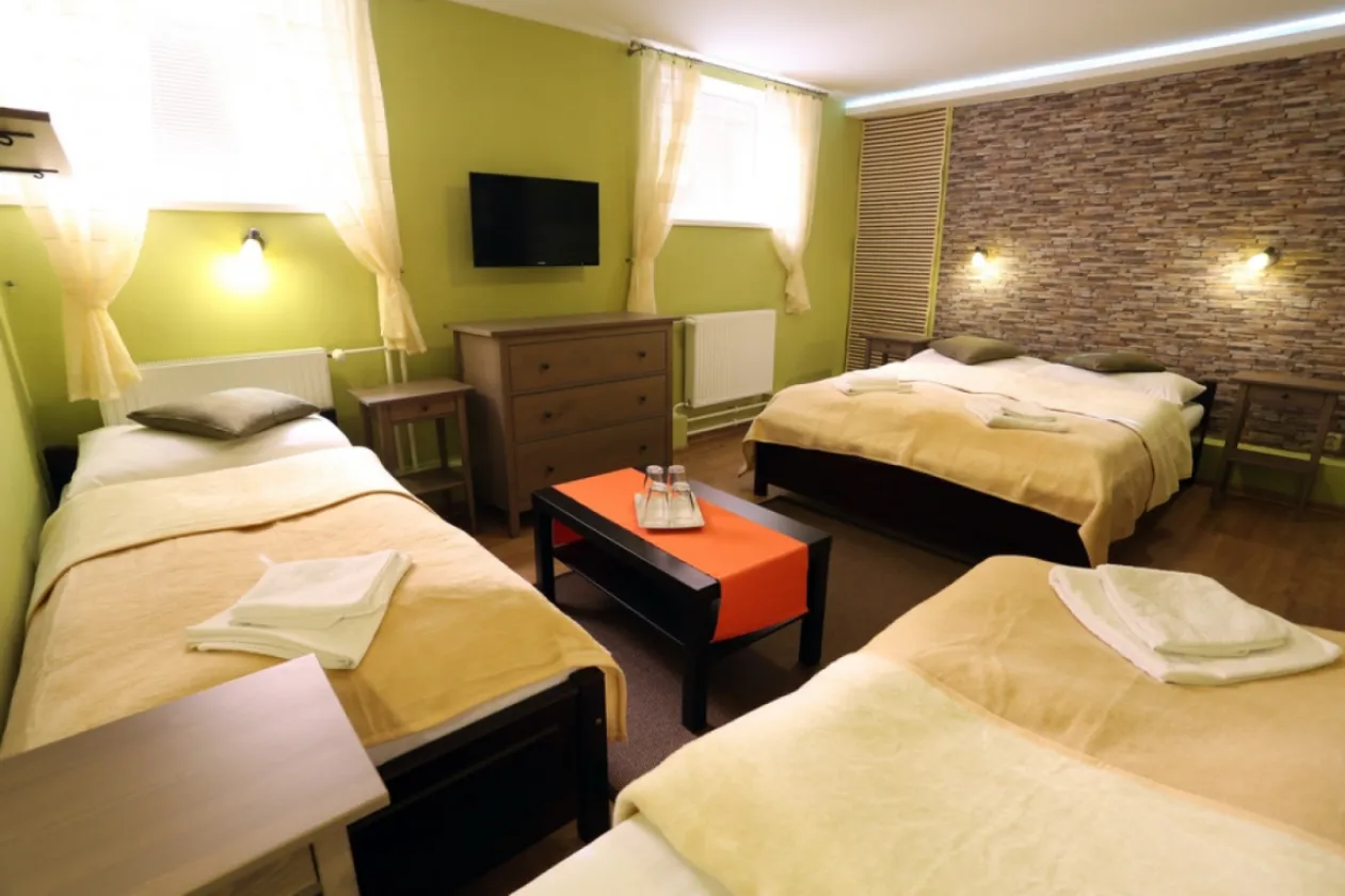 A guest house room with two beds, a writing desk and glazed balcony doors