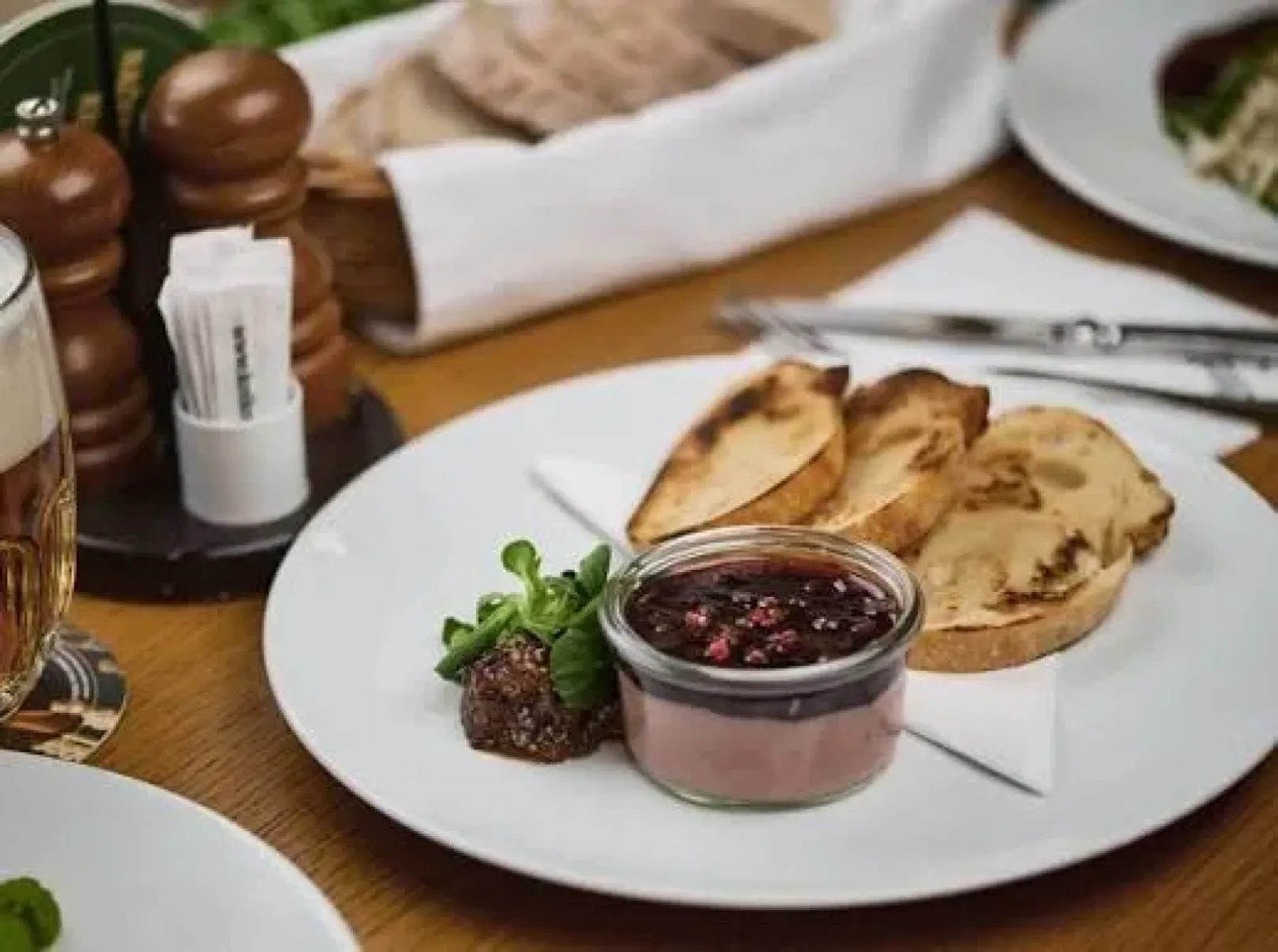 Pâté with cranberry chutney and toast on a plate beside a glass of beer